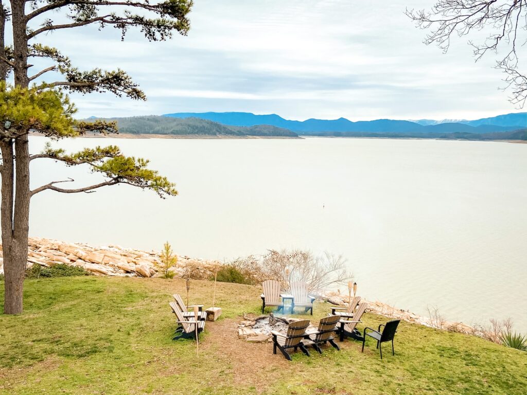 brown wooden table and chairs on green grass field near lake during daytime